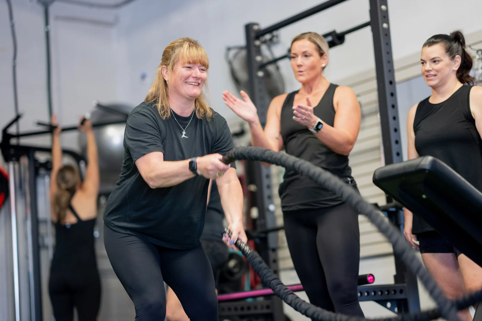 A KLT Fit member working through a coached strength session while the group cheers her on